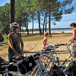 Eine Strandansicht mit abgestellten Fahrrädern und Personen in der Nähe des Wassers.