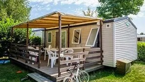 Ein Wohnmobil mit überdachter Veranda, einem Fahrrad und einer kleinen Terrasse.