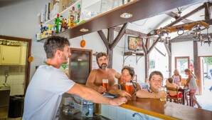 Eine Bar mit einer Theke, Regalen voller Flaschen und einem Fernseher.