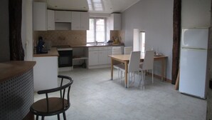 A kitchen with a dining table, chairs, a refrigerator, and a window.