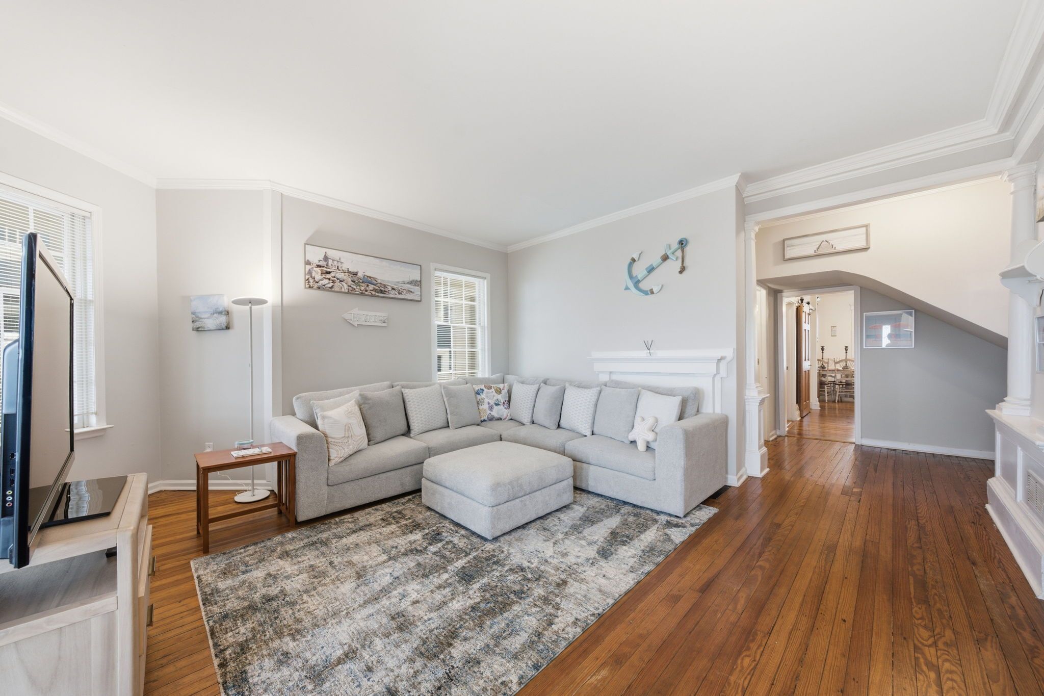 A living room with a sectional sofa, a small table, a rug, and a staircase leading to another level.