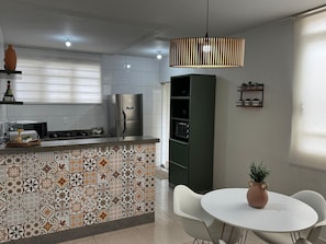 A modern kitchen with a tiled backsplash, a built-in refrigerator, and a dining area with a white table and chairs.