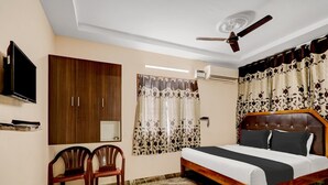 A bedroom with a bed, a ceiling fan, a TV, a wardrobe, and a window with curtains. - Deluxe OYE Stays Visakhapatnam (Visakhapatnam)