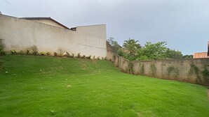 Uma área gramada com um muro de concreto e um edifício ao fundo.