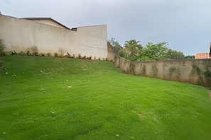 A grassy area with a concrete wall and a building in the background.