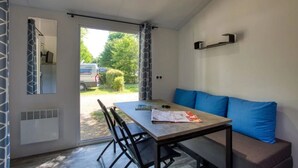Et værelse med et bord, stole, en bænk og en sofa, samt udsigt udad.