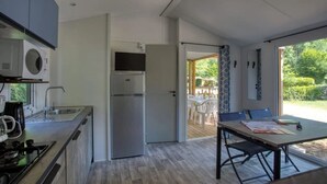 Et moderne køkken med indbygget mikrobølgeovn, køleskab og komfur. Der er et spiseområde med et bord og stole, samt udsigt til det fri.