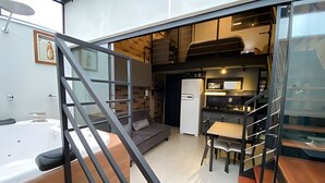 Um interior moderno com escada, sofá, cozinha e mesa de jantar.