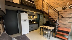Uma cozinha compacta com geladeira, micro-ondas e área de refeições com cadeiras e mesa.