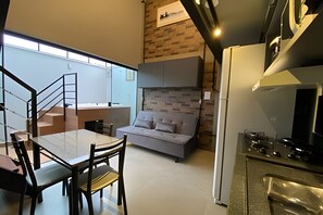 Une cuisine moderne équipée d’une cuisinière à gaz, un coin repas avec une table et des chaises, un canapé et un escalier menant à l’étage supérieur.