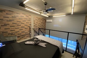 Une chambre d’hôtel avec un mur en briques, un lit avec une couverture, un ventilateur de plafond et une fenêtre donnant sur un paysage agréable.