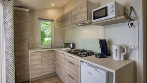 Eine kompakte Küche mit Gasherd, Mikrowelle, Wasserkocher und kleinem Kühlschrank.