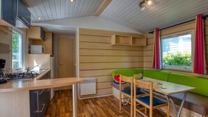 A compact kitchen with a gas stove, a microwave, and a window with curtains. - Camping 3 étoiles - Piscine  - ccbfgfb (Groléjac)