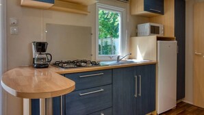 A compact kitchen with a gas stove, a coffee maker, a microwave, and a refrigerator. - Camping 3 étoiles - Piscine  - ccbfgfb (Groléjac)