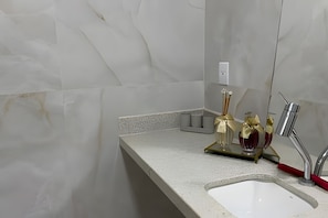A bathroom with a white sink, a mirror, and a towel rack.