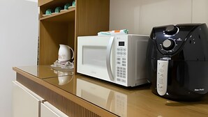 A kitchen with a microwave and a coffee maker on a wooden countertop.
