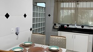 A modern kitchen with white cabinets, a built-in oven, and a window with a curtain.