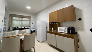 A compact kitchen with a dining area, white cabinets, a microwave, and a refrigerator.