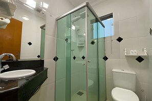 Ein Badezimmer mit Duschkabine aus Glas, einer weißen Toilette und einem Waschbecken mit schwarzer Arbeitsplatte.