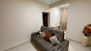 A modern living room with a grey sofa, a small table, and a decorative vase.