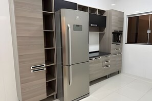 A modern kitchen with built-in appliances, open shelving, and a microwave.