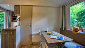 Une cuisine compacte équipée d’un micro-ondes encastré, d’une petite table à manger et d’une fenêtre donnant sur un espace verdoyant.