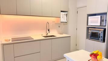 A modern kitchen with a built-in microwave, oven, and sink.