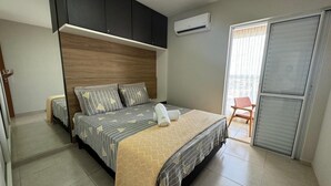 Ein Schlafzimmer mit Bett, Kleiderschrank, Klimaanlage und einer Schiebetür zum Balkon.