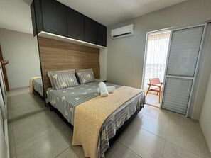 Una camera da letto con un letto, un armadio, un condizionatore d'aria e una porta scorrevole che dà su un balcone.