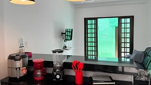 Et moderne køkken med kaffemaskine, blender og en rød utensilholder.