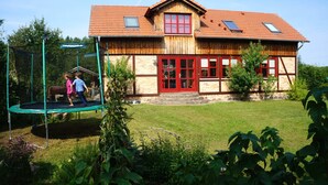 A wooden house with a red door, a swing set, and a well-maintained lawn.