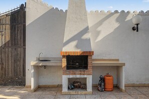 Cocina exterior con horno de ladrillo, pileta y cilindro de gas.