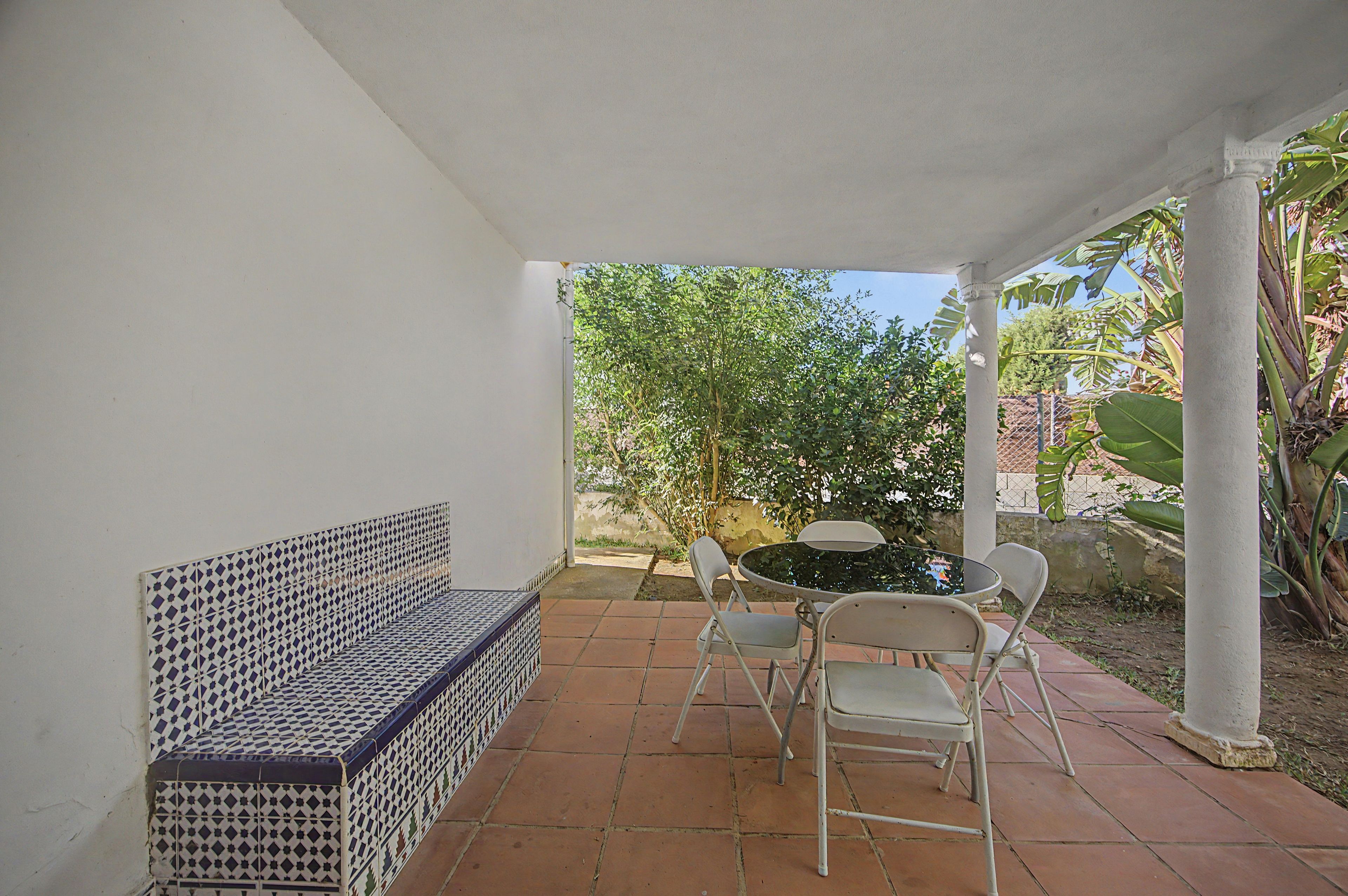 A covered patio with a bench, a table, and chairs.