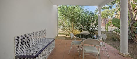 A covered patio with a bench, a table, and chairs.