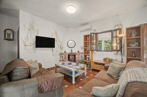 A living room with a television, a fireplace, and a bookshelf. - Country House 'La Hacienda Campo De Borja' with Private Pool, Wi-Fi & Air Conditioning (Conil de la Frontera)