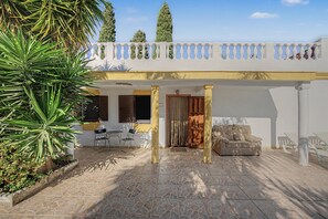 Un espace extérieur aménagé, abrité et doté d’un sol en pierre, d’un canapé et d’une table avec des chaises.