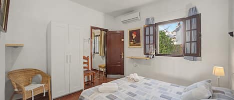 A bedroom with a bed, a chair, a wardrobe, a door, and a window.