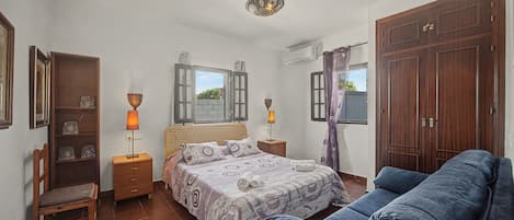 A bedroom with a bed, two bedside tables, a wardrobe, a chair, and a window with curtains.