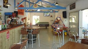 A bar area with stools, a pool table, and a television screen. - Camping 4 étoiles - Piscine  - ccbfhbe (Badefols-sur-Dordogne)
