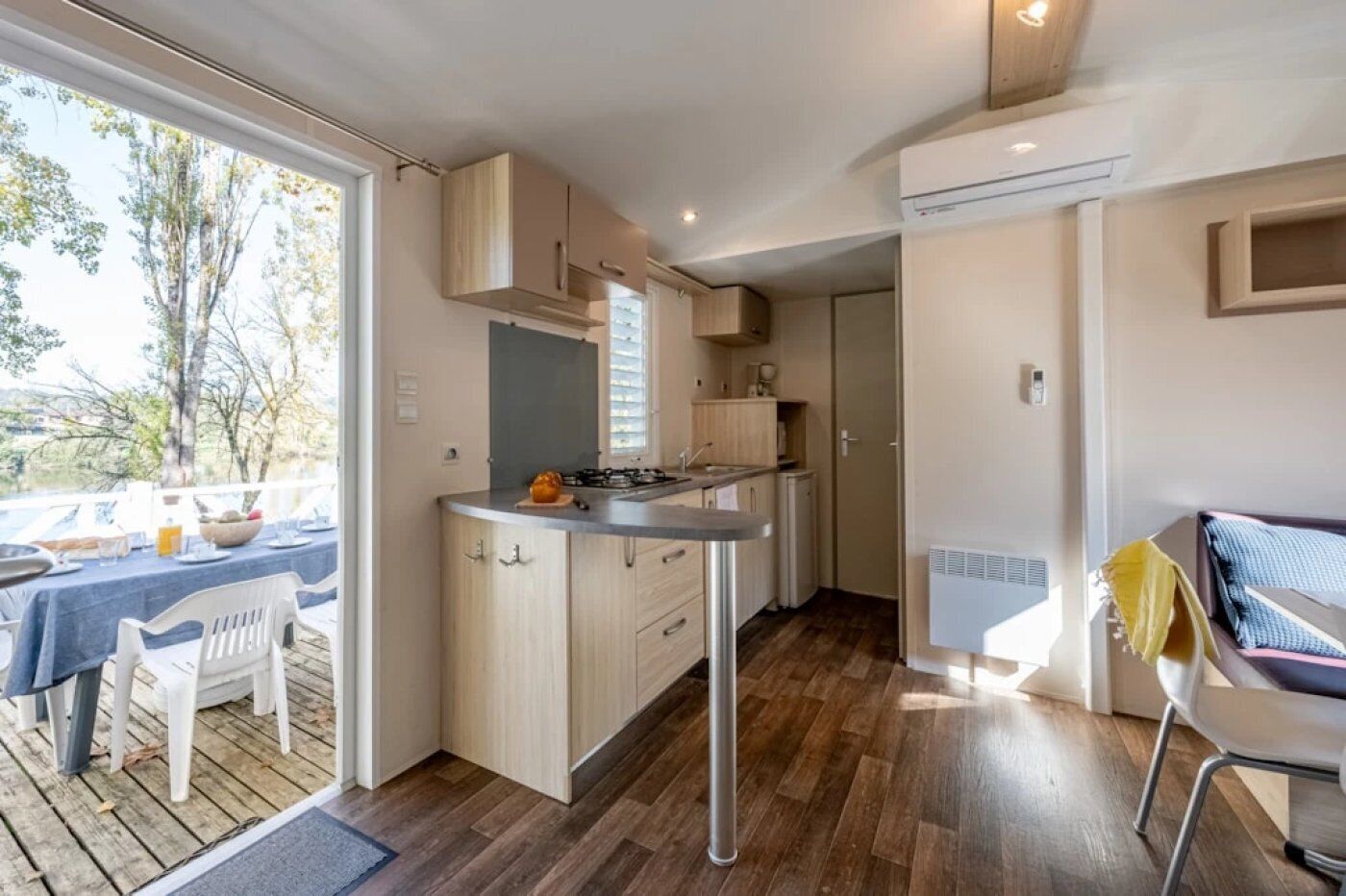 A compact kitchen with wooden cabinets, a central island, and a dining area with a table and chairs.