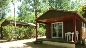 A small cabin with a porch, two chairs, and a table.