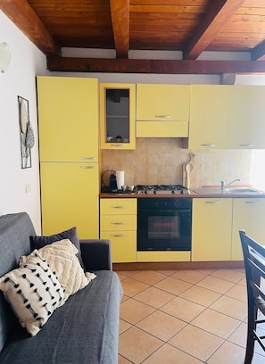 Een kleine keuken met gele kastjes, een fornuis en een spoelbak.