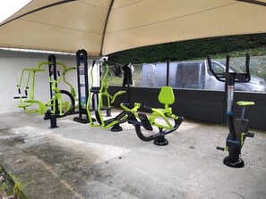 Équipement de fitness installé à l’extérieur, sous une structure abritée.