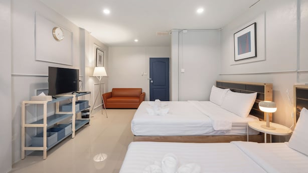 Una habitación de hotel con dos camas, televisión, escritorio, silla y puerta.
