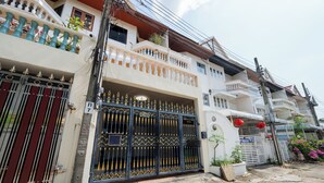 Un edificio residencial de varios pisos con entrada protegida por un portón, balcones y un poste de electricidad visible.