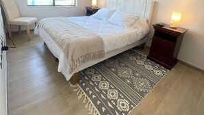 A bedroom with a bed, bedside tables, a chair, a window, and a patterned rug. - Modern 1D1B apartment with fully furnished parking. (Los Angeles)