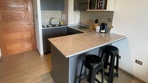 A modern kitchen with a central island, bar stools, and built-in appliances. - Modern 1D1B apartment with fully furnished parking. (Los Angeles)