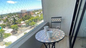 A balcony with a round table and two chairs, a small potted plant, and a view of a cityscape. - Modern 1D1B apartment with fully furnished parking. (Los Angeles)