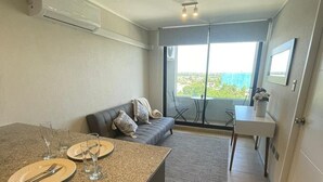 A modern kitchen with a dining area, a sofa, and a view through a large window. - Modern 1D1B apartment with fully furnished parking. (Los Angeles)
