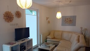 Un salon moderne avec un téléviseur à écran plat, un canapé, une table basse et des œuvres d’art décoratives au mur.
